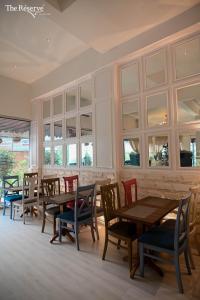 卡拉奇The Reserve Boutique Hotel的餐厅设有木桌、椅子和窗户。