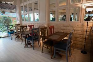 卡拉奇The Reserve Boutique Hotel的餐厅设有木桌、椅子和窗户。