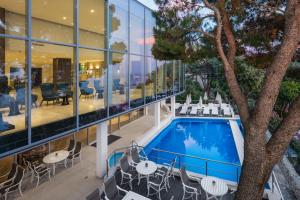 杜布罗夫尼克Royal Ariston Hotel的享有带游泳池和桌椅的建筑的景致。
