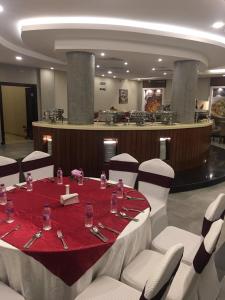 吉赞Al Maali Hotel Jazan的一间设有红色桌子和白色椅子的用餐室