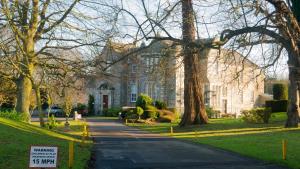 Kilconquhar基尔康克尔城堡酒店的一条有绿树成荫的车道的大型白色建筑