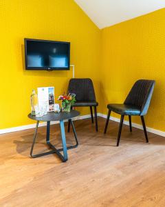 米德尔堡Hotel Brasserie de Huifkar的黄色墙壁上设有两把椅子和一张桌子及电视