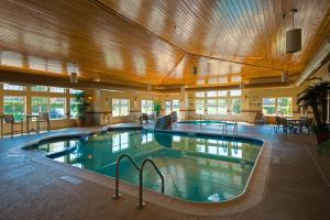 Roselle芝加哥罗塞尔西智选假日酒店的一座大型室内游泳池,位于一栋带木制天花板的建筑内