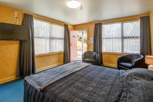 蒂阿瑙红草丛汽车旅馆的一间卧室配有一张床、两把椅子和窗户