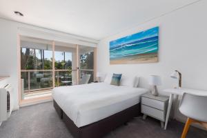 科夫斯港查尔斯沃思湾海滩度假酒店的一间卧室配有一张床、一张书桌和一个窗户。