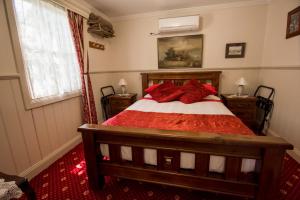 沃尔哈拉Mill house的一间卧室配有一张带红色枕头的床和一扇窗户