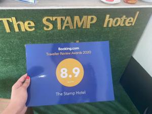 涛岛The Stamp Hotel的持有印花酒店标志的人