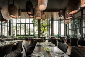 北芭堤雅Cape Dara Resort - SHA Plus的餐厅设有桌椅和大窗户。