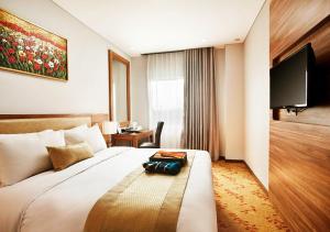 日惹Grand Serela Yogyakarta by KAGUM Hotels的酒店客房设有一张大床和电视