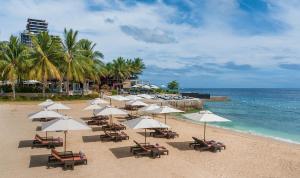 麦克坦Crimson Resort and Spa - Mactan Island, Cebu的海滩上设有椅子和遮阳伞,还有大海