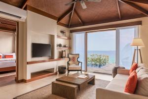 麦克坦Crimson Resort and Spa - Mactan Island, Cebu的带沙发、电视和床的客厅