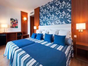 圣苏珊娜塔希提普拉亚酒店的一张蓝色和白色的床,位于酒店客房内