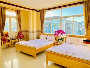 芹苴Mekong Rose Hotel的带窗户和鲜花的客房内的两张床