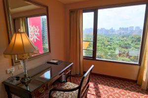 台北丽都唯客乐饭店的酒店客房设有一张书桌和一个大窗户。