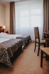 波兹南科瑞尔酒店的卧室配有床、椅子和窗户。