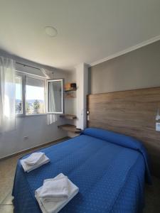 波尔托马林波尔托米诺旅馆的一间卧室配有蓝色的床和2条毛巾