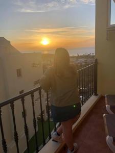 滨海帕尔姆Laderas del Palmar的站在阳台上欣赏日落的女人