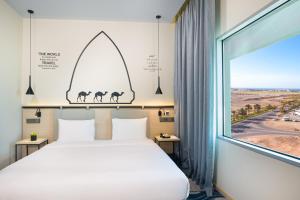 马斯喀特Swiss-Belinn Airport Muscat Oman的一间卧室设有一张床和一个大窗户