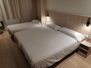巴塞罗那奎尔伯爵旅馆的配有白色床单的酒店客房内的两张床