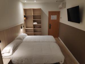 巴塞罗那奎尔伯爵旅馆的一间卧室配有两张白色的床和电视