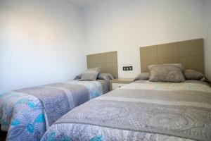 科尼尔-德拉弗龙特拉Villa Nueva Cascada - Casa Rustica "Tu Casa En Conil"的卧室内的两张床,配有蓝色和灰色的毯子