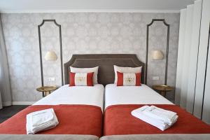 里斯本Famous Crows Lisbon Suites的一间卧室配有两张带红白色枕头的床