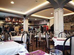 巴萨Hostal Los Hermanos的一间设有白色桌椅的餐厅,可容纳众多客人。