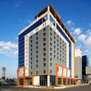 吉达Adagio Jeddah City Center的一座高大的建筑,旁边是钟