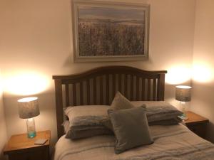 BunaveneadarSOLACE COTTAGE的一间卧室配有一张带两盏灯和一幅画的床铺