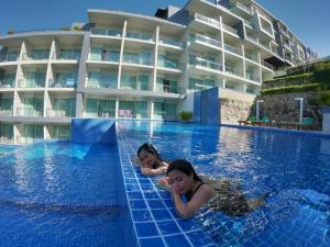卡塔海滩Sugar Palm Grand Hillside - SHA Plus的两个女孩在一家酒店的游泳池游泳