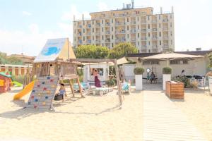 利多克拉西Hotel Adler的沙地的游乐场,带滑梯和建筑物