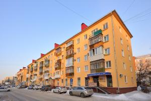 鄂木斯克Omsk Sutki Apartments at Pushkina 99 floor 4的一条有停车车的街道上的橙色建筑