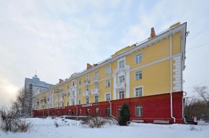 鄂木斯克Apartment Karla Marksa 22的雪中一座黄色和红色的大建筑
