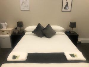 悉尼Wentworth Hotel的卧室配有一张带黑色枕头的大型白色床。