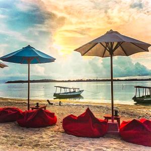 吉利阿尔班兰简易别墅的沙滩上,沙滩上摆放着两把遮阳伞和红色毯子
