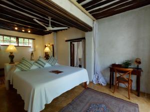 ShelaPeponi Hotel Lamu - Kenya的卧室配有一张白色大床和一把椅子