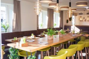 萨尔茨堡珀斯特绿色酒店 - 100％比奥的用餐室配有大型木桌和黄色椅子