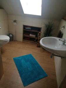 NeudörflesStadler Ferienwohnung的设有带水槽和卫生间的浴室以及蓝色地毯。