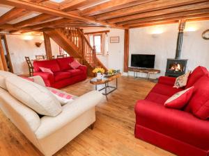哈佛威斯特Cowslip Cottage的客厅设有2张红色的沙发和壁炉