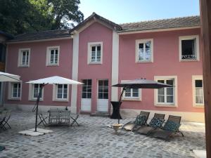 利勒阿当Les 7 Sources的粉红色的建筑,配有桌椅和雨伞