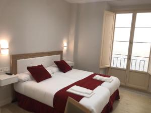 马拉加皮纳尔马拉加中心公寓酒店的一间卧室配有一张带红色和白色枕头的大床