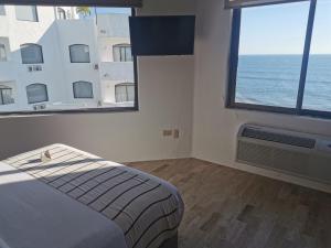 马萨特兰Gaviana Resort的一间卧室设有一张床和两个大窗户