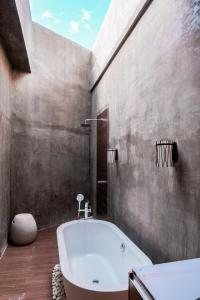 爱妮岛Charlie's El Nido Managed by HII的一间带白色浴缸和混凝土墙的浴室