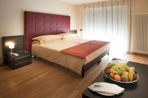 阿尔巴卡利萨诺公寓式酒店的一间卧室配有一张床,桌上放着一碗水果