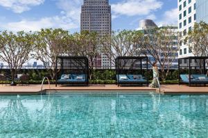 曼谷Carlton Hotel Bangkok Sukhumvit的一个带椅子的大型游泳池,享有城市天际线