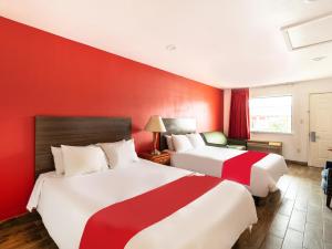 圣安东尼奥OYO Hotel San Antonio near AT&T Center的红色墙壁的酒店客房内的两张床