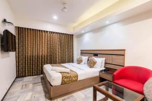 孟买Hotel Avon Ruby Dadar的酒店客房,配有一张床和一张红色椅子