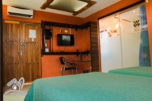 VillamontesEco Hotel Gota del Chaco的一间卧室配有一张床、一台电视和一扇门