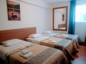 利马利马巴黎酒店的带三张床和镜子的客房