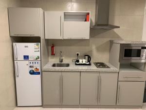 吉达Manazelna Aparthotel的厨房配有白色橱柜和白色冰箱。